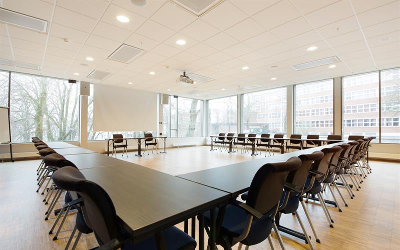 lys og stor konferansesal med bord i hesteskooppsett og konferanseteknikk