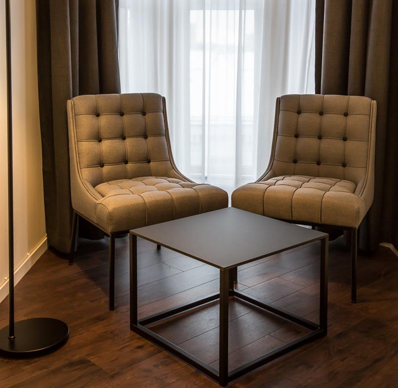To brune stoler, salongbord og lampe foran et vindu. Saga Hotel & Poshtel Oslo Central. Foto
