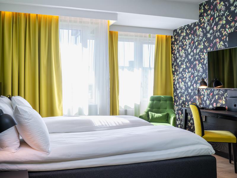 Seng og skrivebord i gult og grønt. Superior room Thon Hotel Gyldenløve. Foto