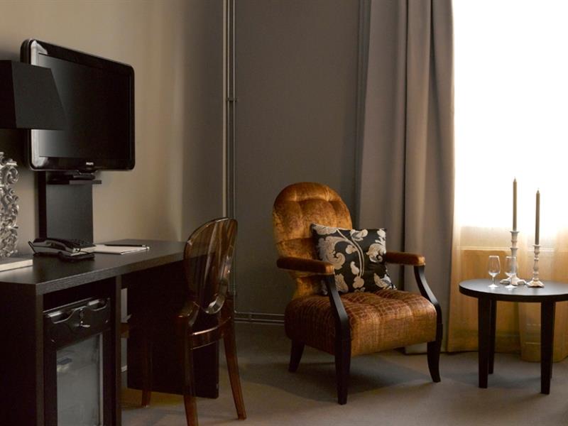 Stol og bord med lyslykt foran vindu- TV på veggen. Saga Hotel Oslo. Foto