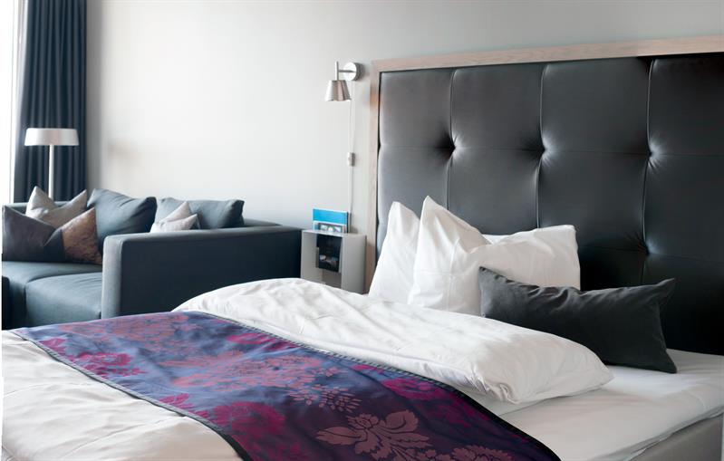 Juniorsuite, seng og sofa, mørk innredning. Foto