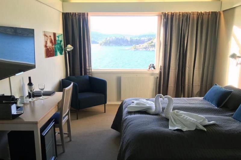 Dobbeltrom med seng, skrivebord, lenestol, TV, håndkle svaner og utsikt over fjorden