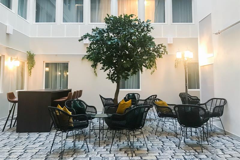 terrasse med et lite tre og sitteplasser 