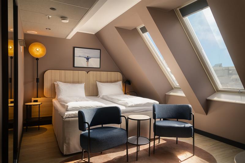 Hotellrom med dobbeltseng, to lenestoler og store vinduer