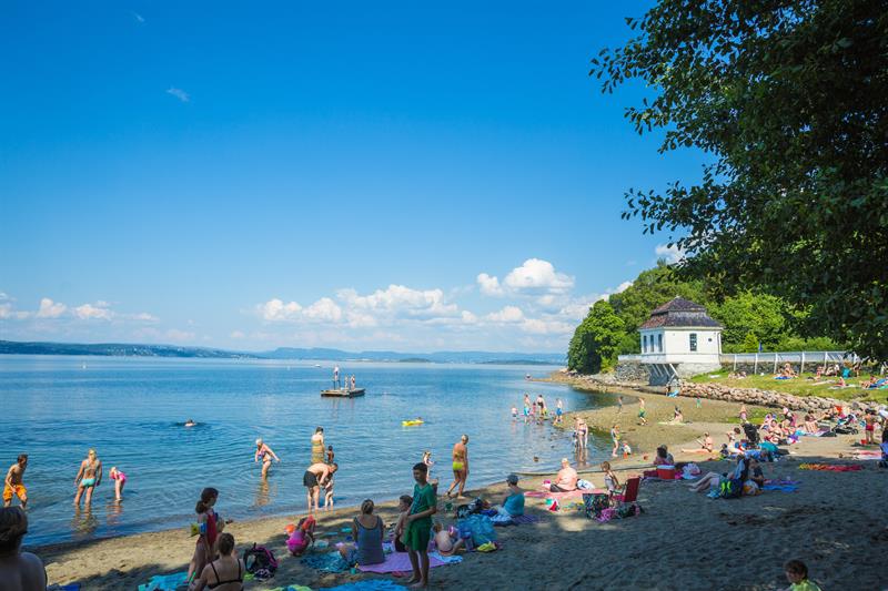 Folk som slapper av på stranden og svømmer i Oslofjorden