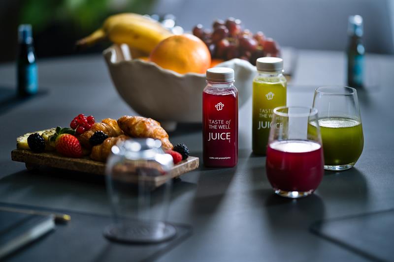 Nærbilde av frukt, croissanter og juiceflasker på et bord.