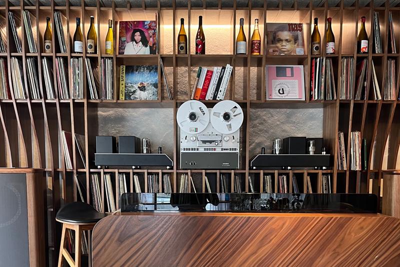 Hyller med vinylplater, stereoanlegg og vinflasker.