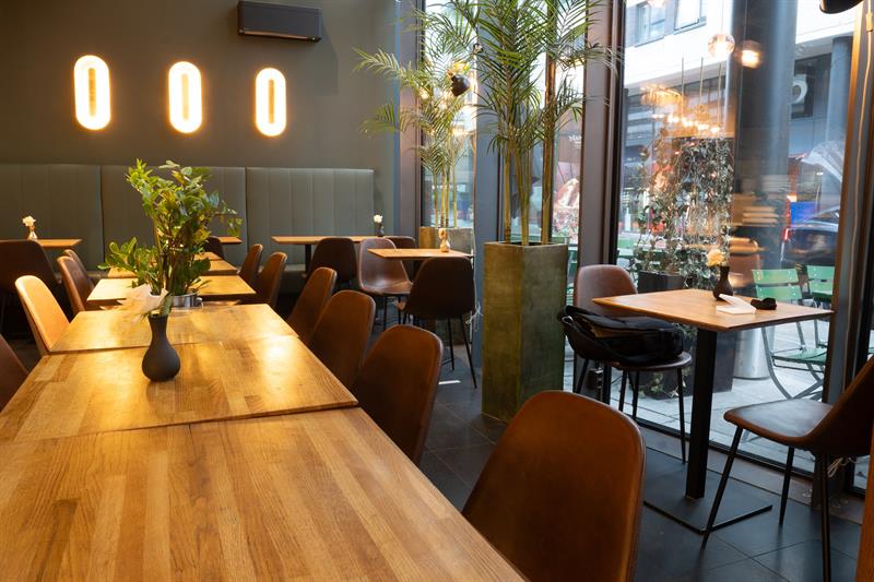 Restaurantinteriør med små spisebord og stoler, store panoramavinduer