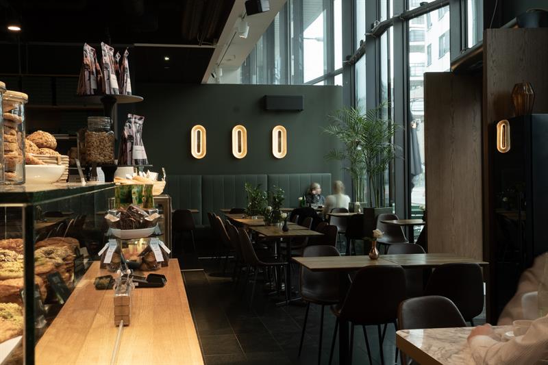 Restaurantinteriør med utstilte bakervarer, disk og små spisebord
