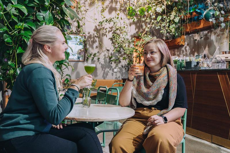 To jenter som drikker cocktailer ved baren