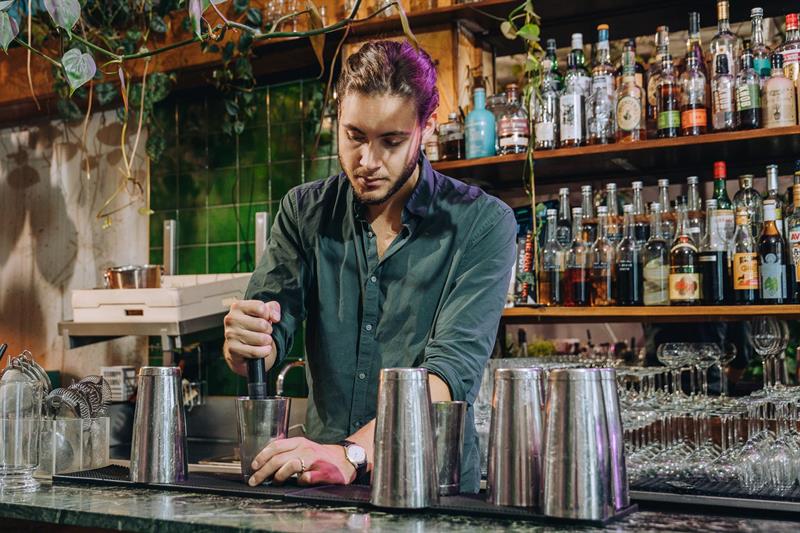 En bartender bak baren som blander en drink