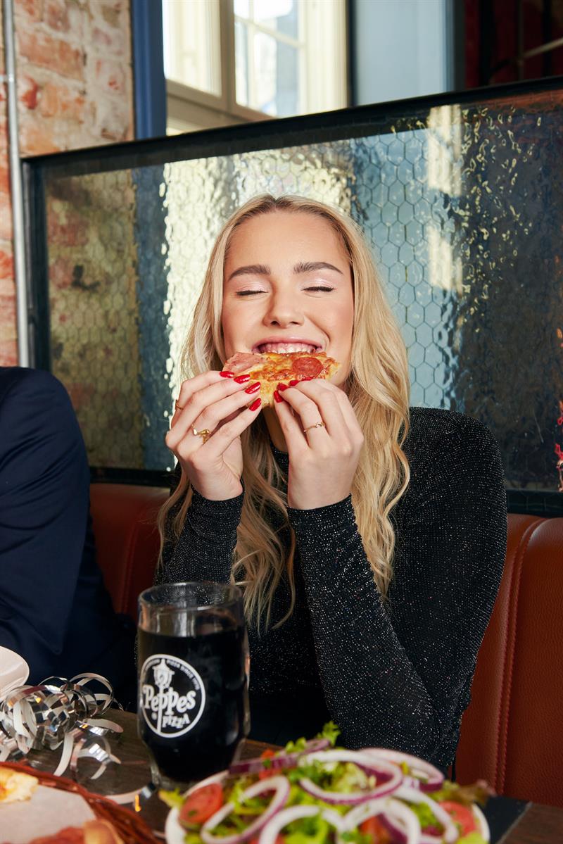 En jente som spiser et stykke pizza.