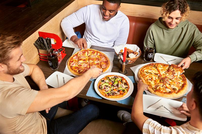 Fire personer som spiser pizza sammen.