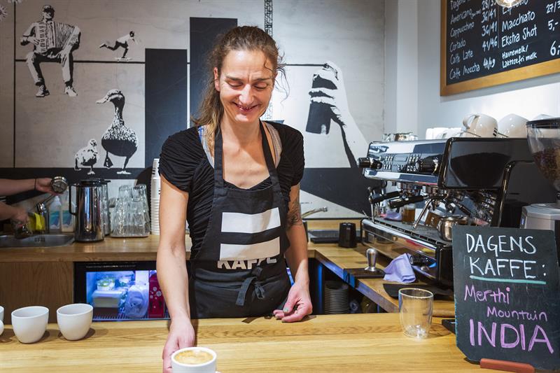 En barista som serverer en kopp cappuccino.