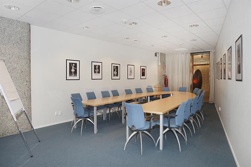 Konferanserom med et langt bord i U-form.