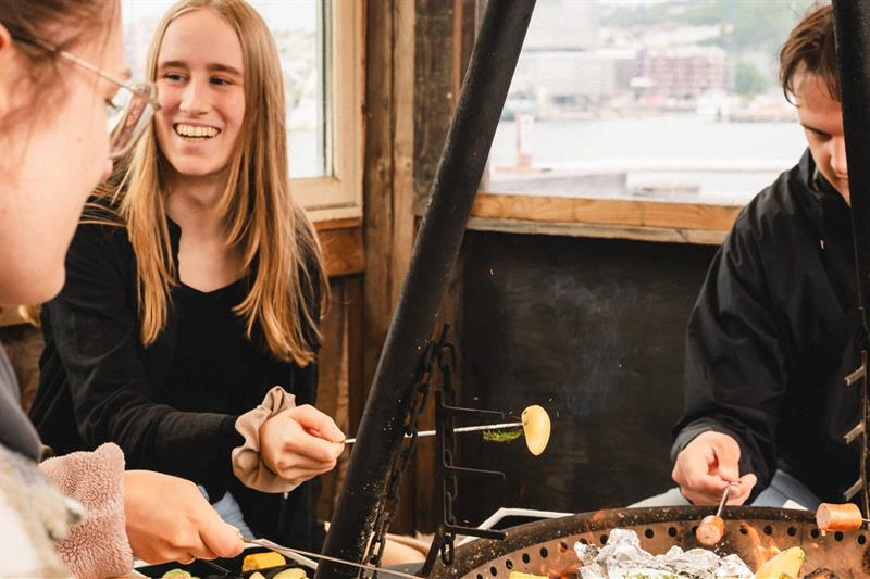 Folk sitter rundt bålplassen
