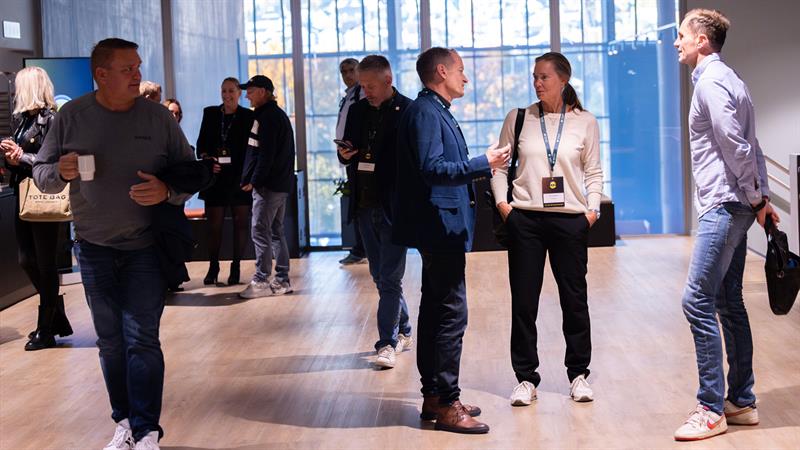 Et åpent nettverksområde med folk som står og snakker sammen på et konferansested.