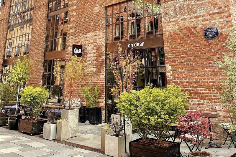 vinbar i en gammel fabrikkbygning med uteservering og planter 