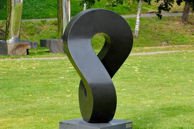 Skulptur i mørkegrå stein. Ligner et oppreist evighetssymbol.