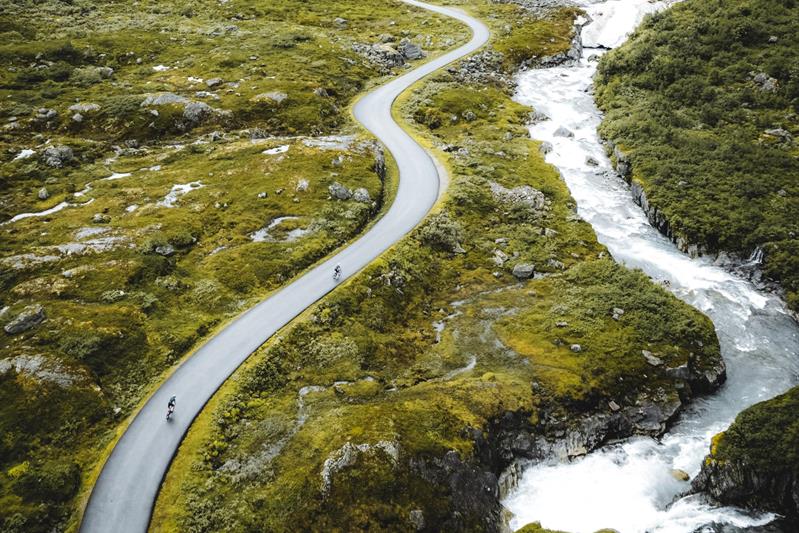 Å sykle langs en landevei med fjellandskapet i bakgrunnen