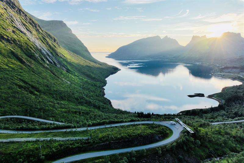 En campingbil som har stoppet ved en innsjø omgitt av store fjell
