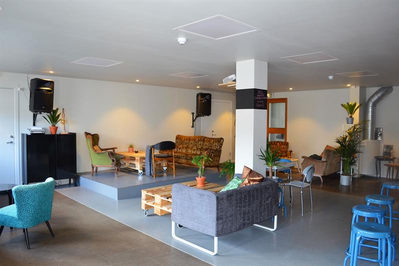 sitteplasser med barstoler, sofaer og lenestoler, samt en liten scene