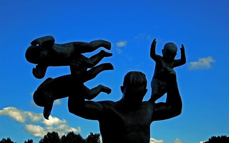 Statue av en voksen mann med tre spedbarn