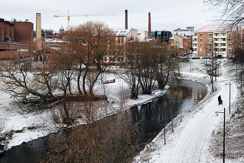 Winter photo of the river with snow. buildings in the background.