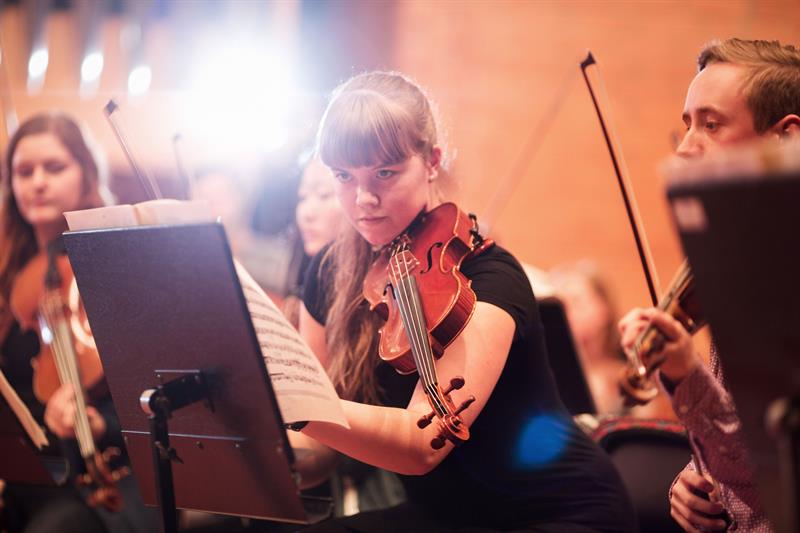 Detail of a woman with a violin in an orchestra