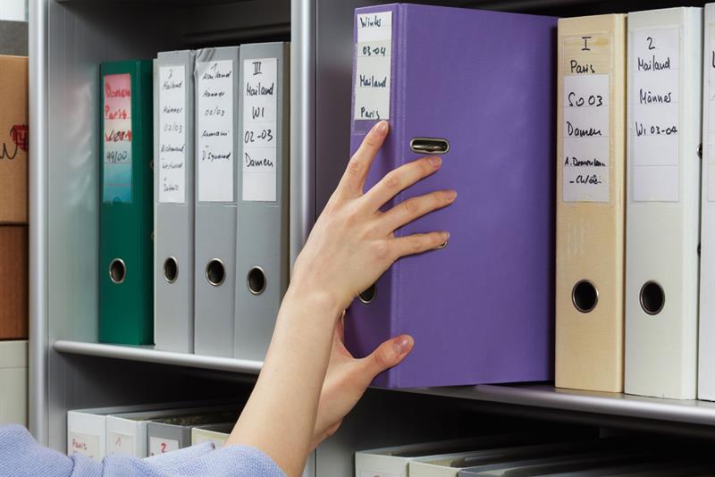 Person pulling a purple binder from a bookcase