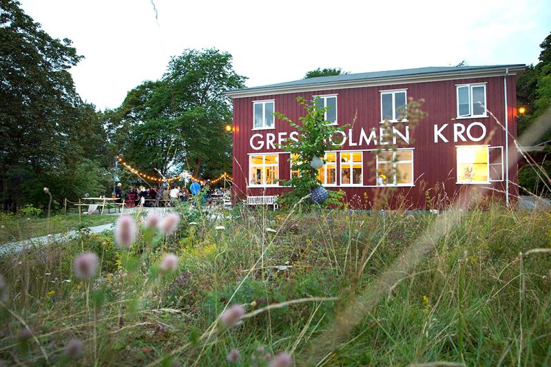 Exterior of Gressholmen Kro with outdoor seating, surrounded by forest.