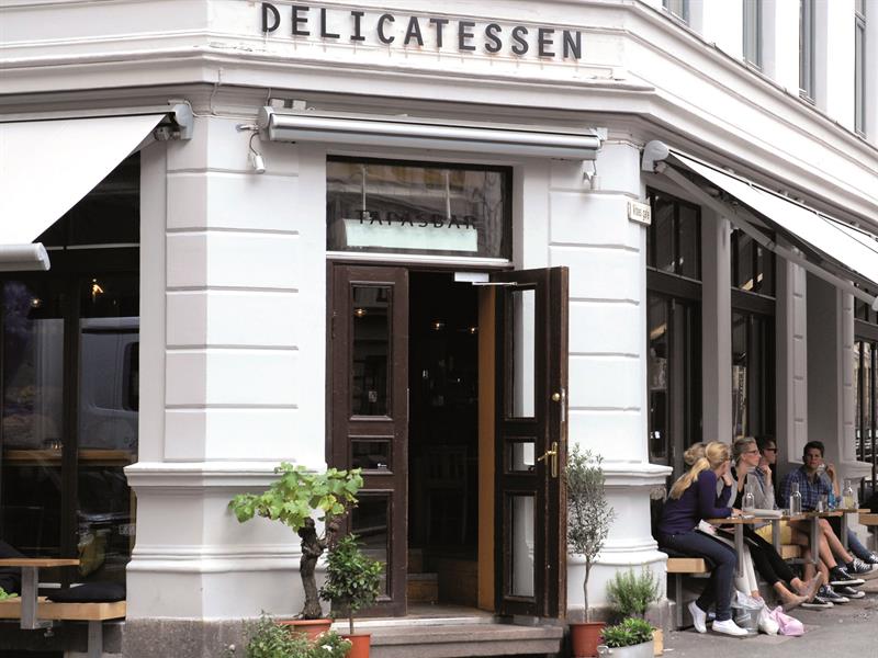 Restaurantens eksteriør - hvit murbygning med uteservering.