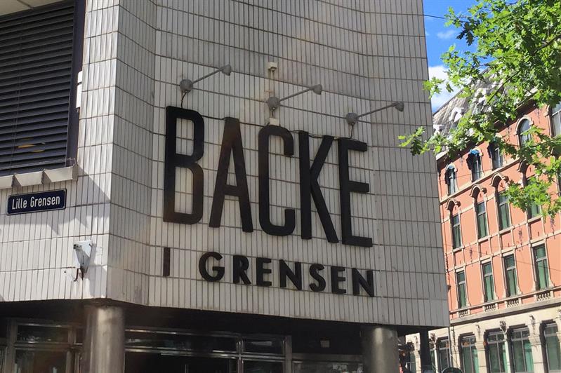 Utsiden av en grå bygning med svart logo.
