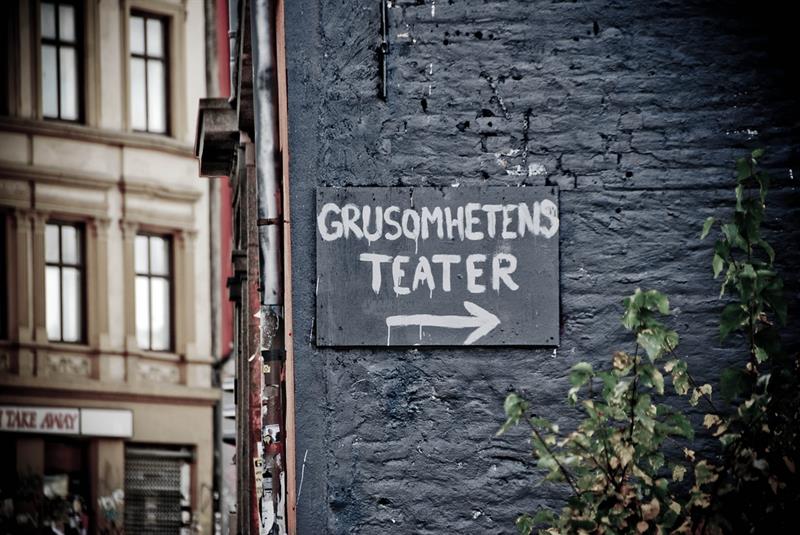 Svart murvegg med et skilt mot Theatre of Cruelty.