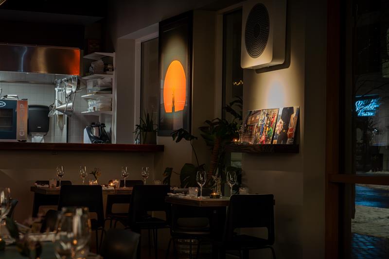 Restaurantinteriør med åpent kjøkken og små bord