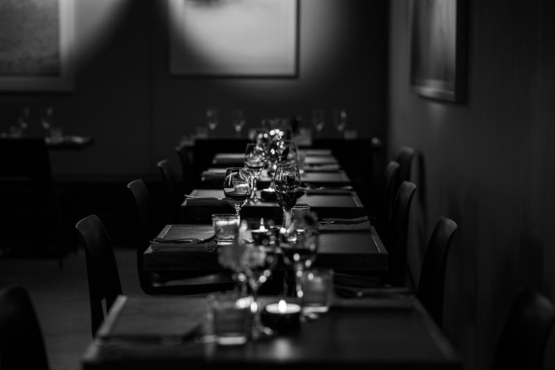 Svart-hvitt foto: Små bord dekket til middag med stearinlys