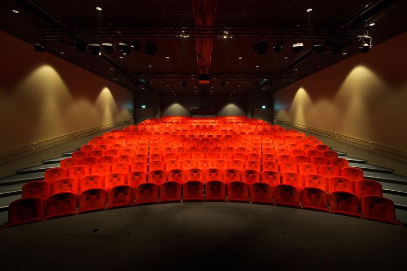 Tomt teater med røde stoler sett fra scenen.
