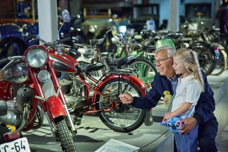 En eldre mann og en liten jente ser på motorsykler.