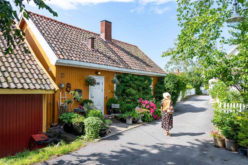 En kvinne går forbi et gult trehus.