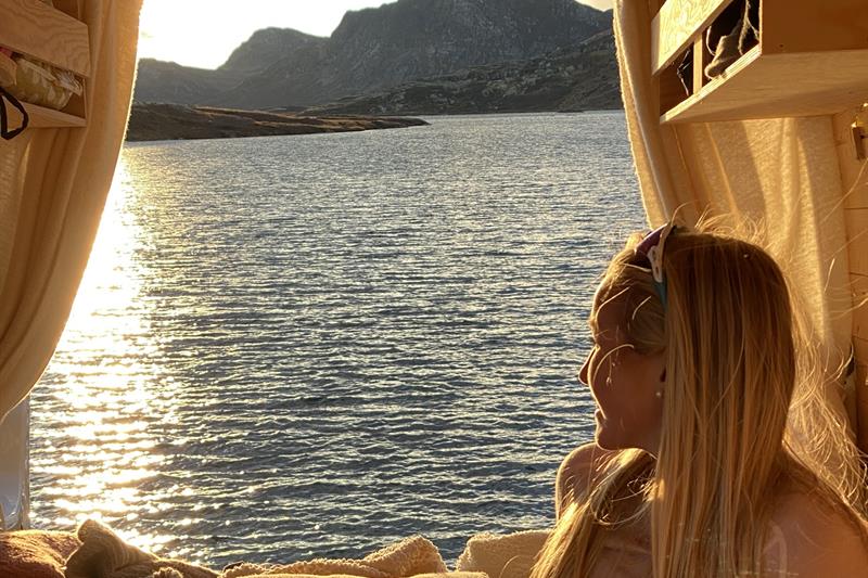 Kvinne ser ut over havet fra bobilen