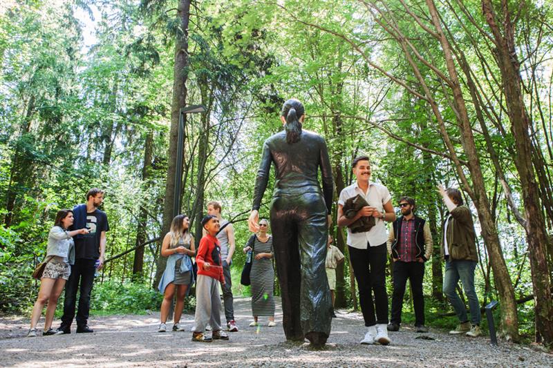 Folk står foran skulpturen "Walking Woman".