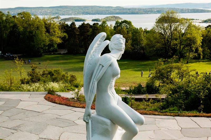 Skulptur av en engel som sitter på en stein.