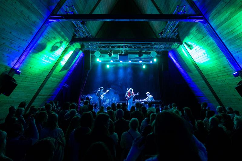 artister på scenen og fullt publikumsområde under en konsert på SALT