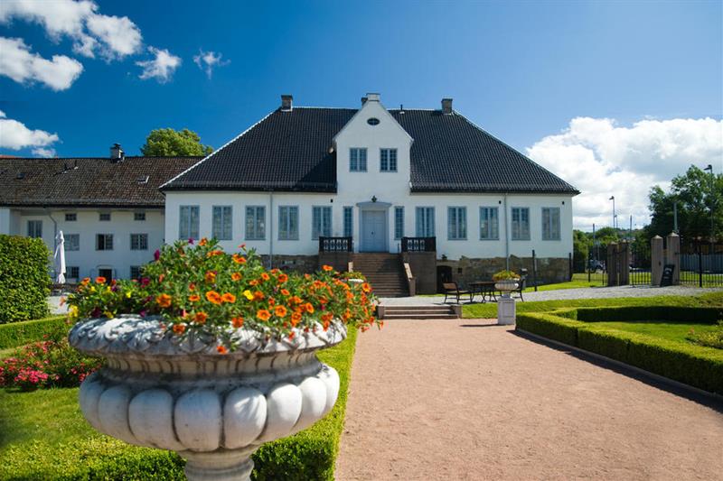 Eksteriør: Hvit herregård fra barokken med en gressplen foran.