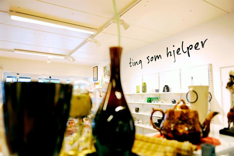 Diverse glass- og porselensgjenstander på en hylle.