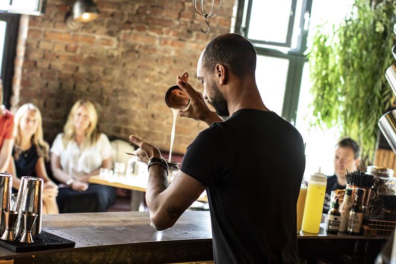 Bartenderen blander en drink.