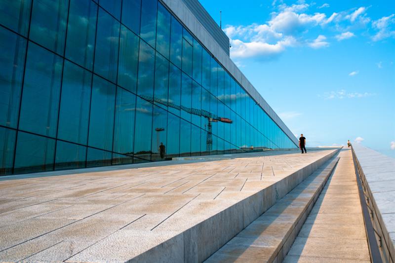 Utvendig bilde av operaen med de store glassvinduene på venstre side.
