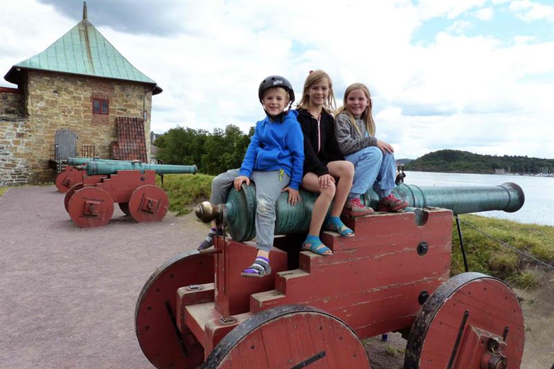 Tre barn sitter på en kanon.