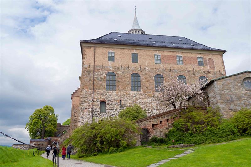 Akershus slott sett fra ormeperspektiv, med folk som går langs slottet på venstre side.
