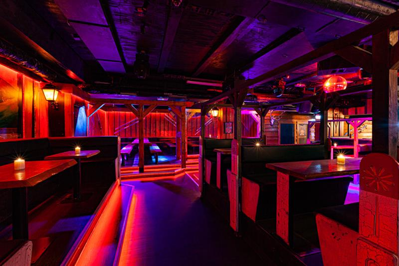 Barinteriør med sitteplasser omgitt av neonlys